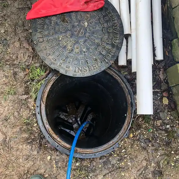 Open inspection chamber with a blue drain jetting hose during drain unblocking in Plymouth.